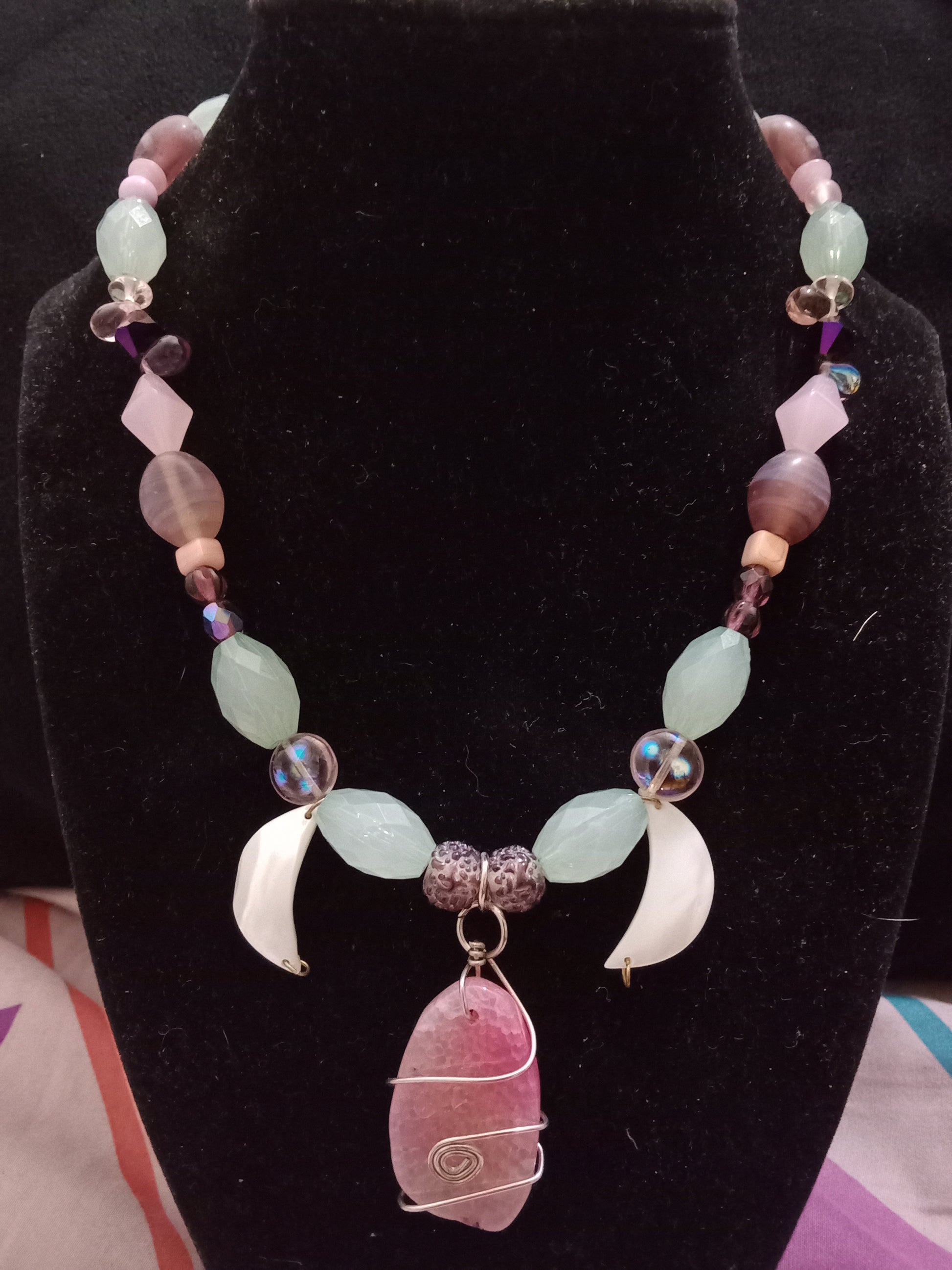 Green, pink, white and purple beads alternating. Pink gold wire wrapped stone as center piece