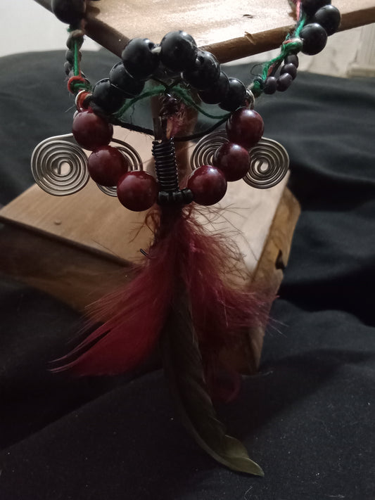 Beaded hemp cord necklace. Feather center piece. Deep red, green and black rounded beads with two double spiraled silver wire charms