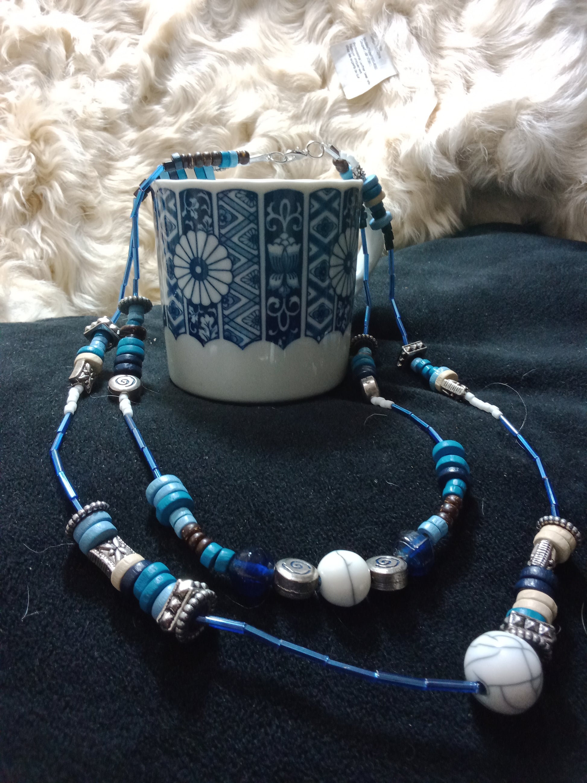 Flex cord beaded necklace consisting of hues of blue various sized beads with silver metal spacer beads. 21 inches.